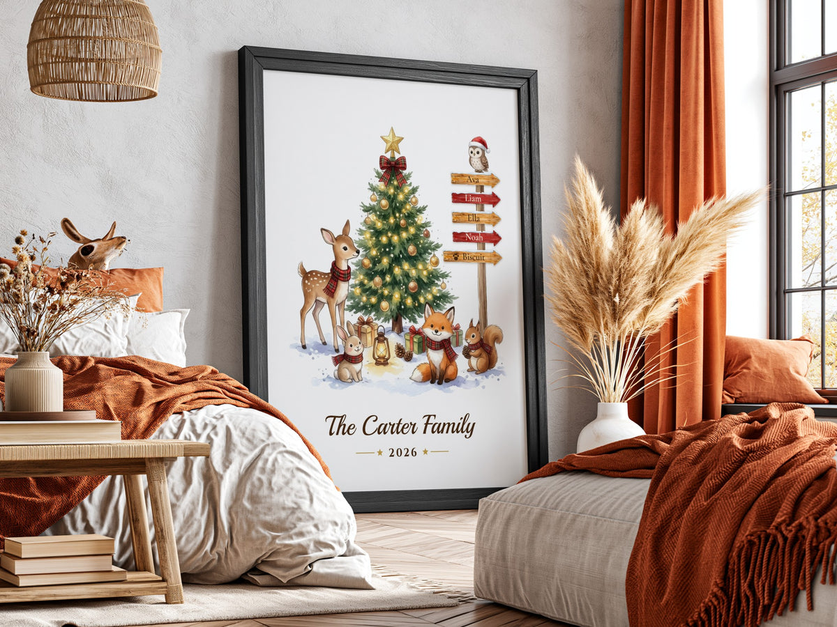 A framed personalized Christmas art print leaning against a wall in a cozy bedroom setting. The print features a watercolor illustration of a decorated Christmas tree with deer, foxes, a squirrel, and an owl, with the text 'The Carter Family 2026' at the bottom.