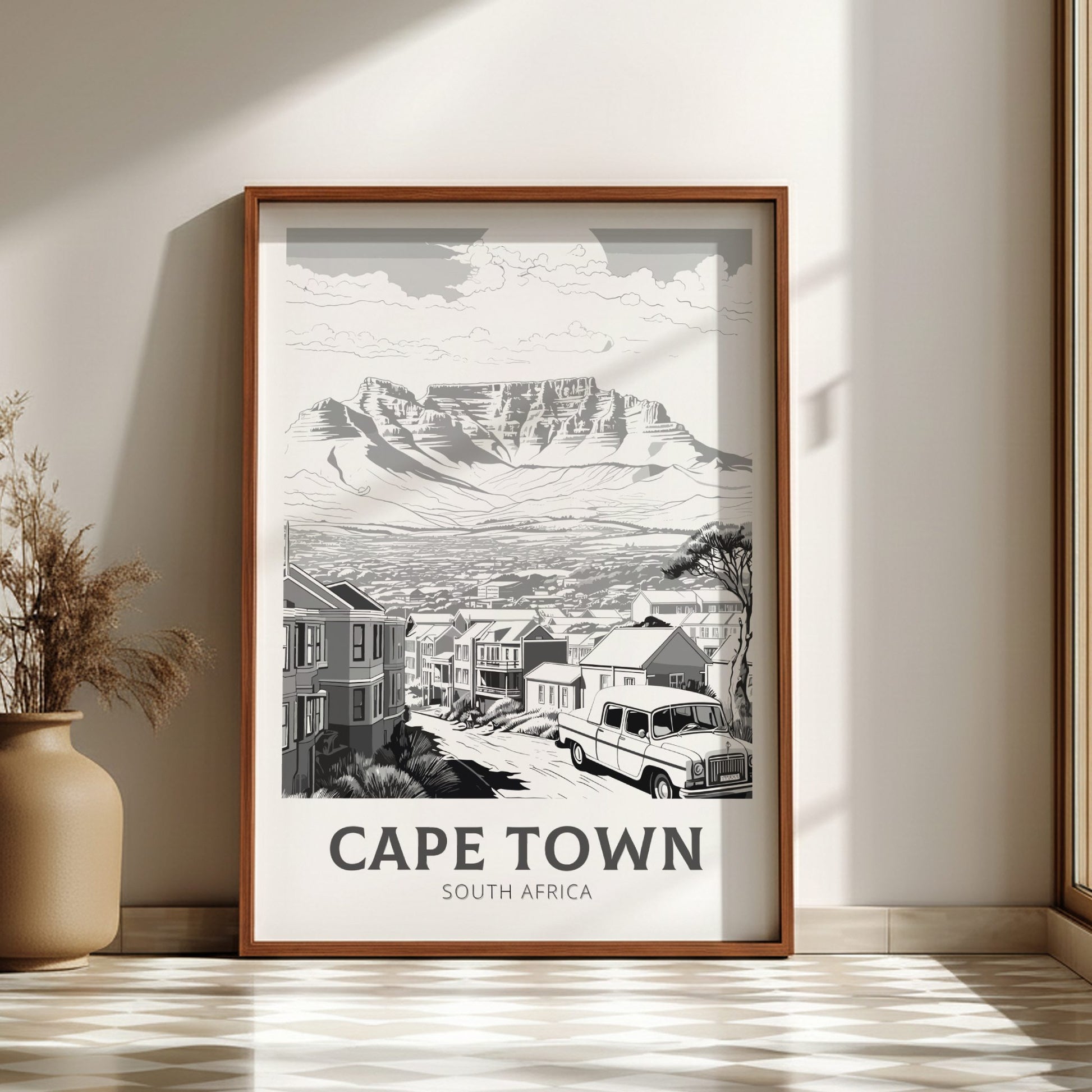 Framed artwork of Cape Town, South Africa, on a wall with a vase and plant.