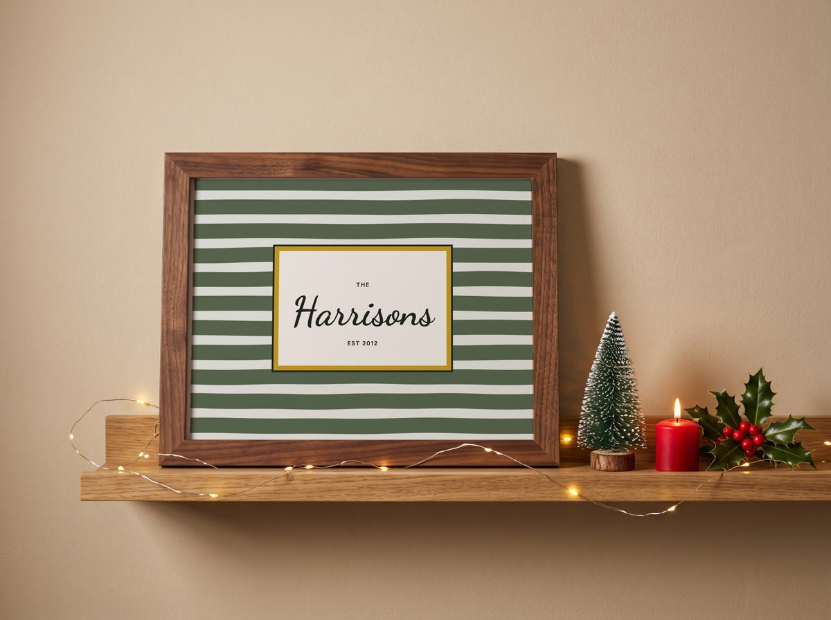 A framed personalized art print with green and white horizontal stripes, a dark wood frame, and a central white label reading 'The Harrisons EST. 2012'.