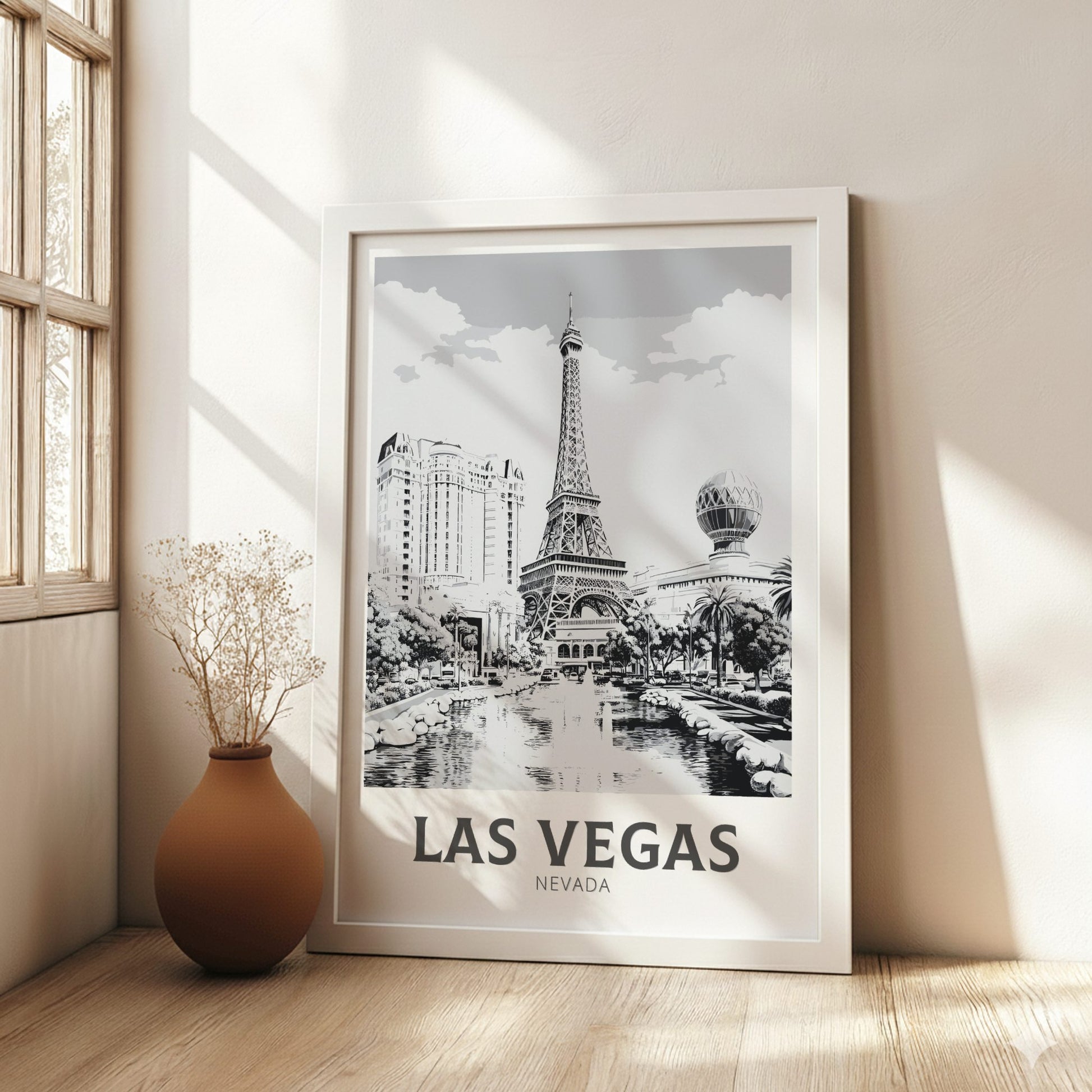 Framed Las Vegas poster on a wall with a vase and plant in the foreground.