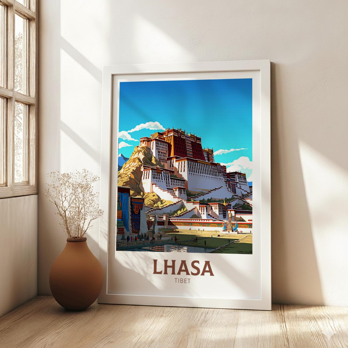 Framed poster of Lhasa, Tibet with a building and blue sky in a room with a vase and plant.