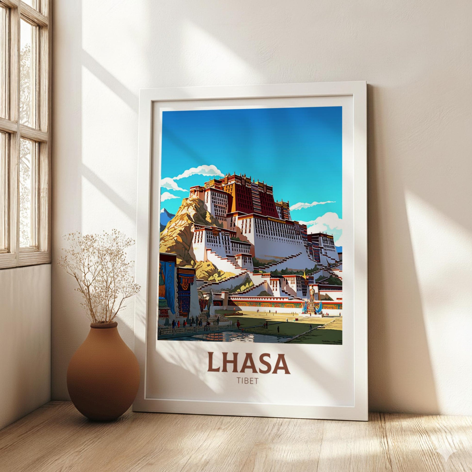 Framed poster of Lhasa, Tibet with a building and blue sky in a room with a vase and plant.